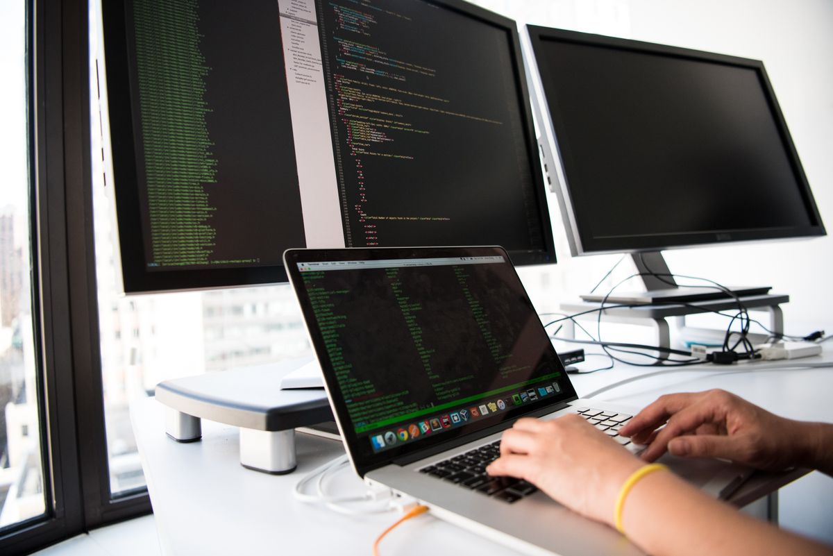 Developer writing PHP and web application code on multiple screens